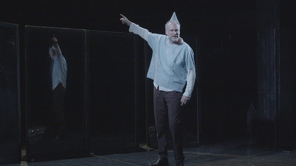 Man in party hat gestures on stage